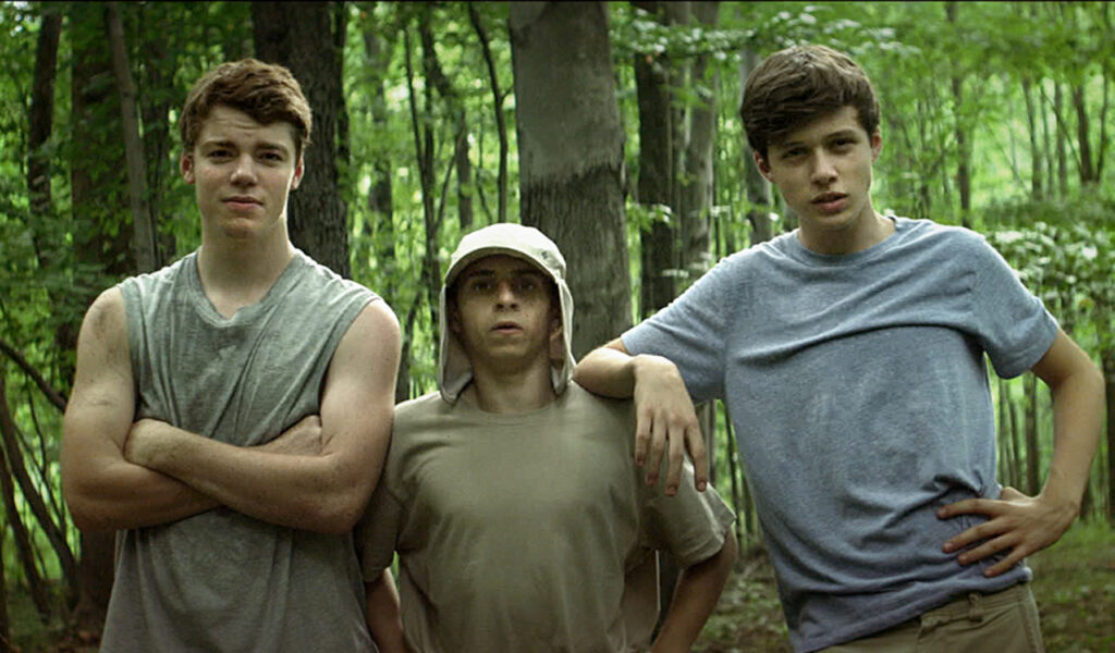 Three boys in a forest looking at something